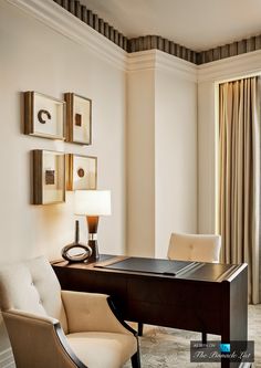 a desk and chair in a room with curtains on the window sill behind it