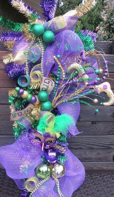 a purple and green christmas tree with ornaments on it's head, in front of a wooden fence