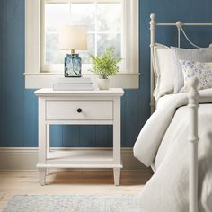 a bedroom with blue walls, white furniture and a lamp on the nightstand next to the bed