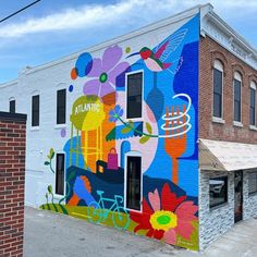 a building painted with colorful flowers and birds on it's side in front of a brick building