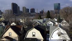 many houses are in the foreground with a large city behind them and trees on the other side