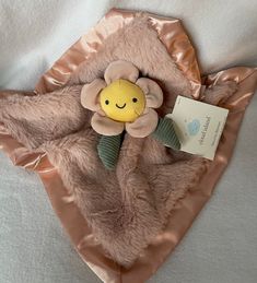 a stuffed animal with a smile on it's face is wrapped in a pink blanket