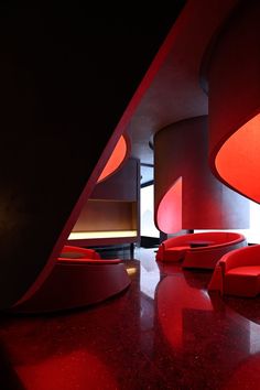 the interior of a modern building with red lighting and circular seating area on the floor