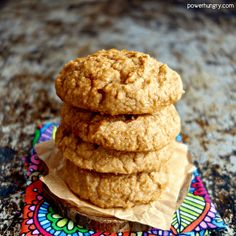 three oatmeal cookies stacked on top of each other in front of a colorful doily