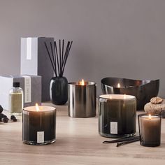 three candles sitting on top of a wooden table next to bottles and other items in front of them