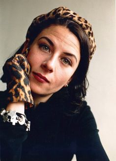 a woman wearing a leopard print headband holding her hand up to her face and looking at the camera