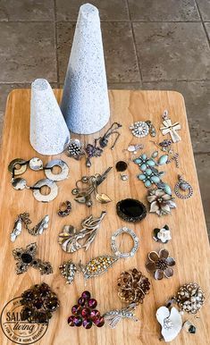 a wooden table topped with lots of different types of rings and earrings on top of it