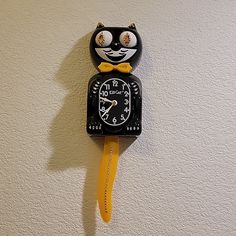 a black and white clock with a cat face on it's face is hanging from the wall