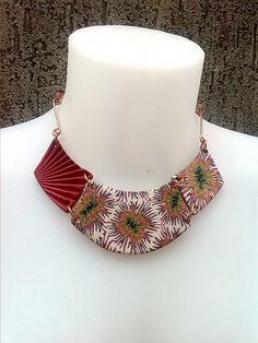 a white mannequin with a red and yellow necklace on it