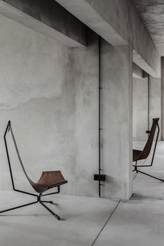 two chairs sitting next to each other on top of cement flooring in an empty room