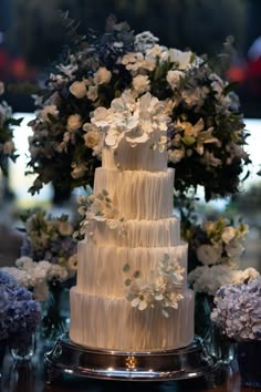 a three tiered white wedding cake surrounded by blue and white flowers