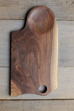 a wooden cutting board sitting on top of a wooden table next to a knife holder