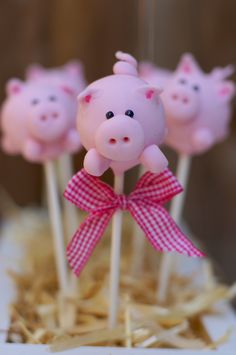 three pink pigs on sticks with a bow