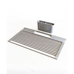 a metal grate and strainer on a white surface with a cup in the background