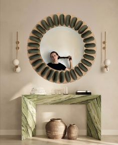 a woman taking a selfie in front of a circular mirror with rocks on it