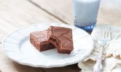 a piece of chocolate cake sitting on top of a white plate next to a glass of water