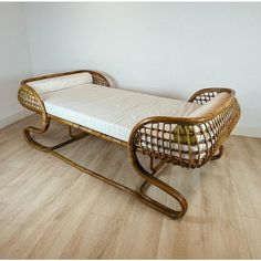 a wicker bed sitting on top of a wooden floor next to a white wall