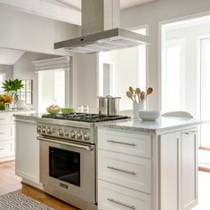 a white kitchen with an oven, stove and counter top in the middle of it