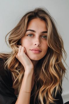 Portrait of a woman with wavy blonde hair and green eyes, resting her chin on her hand, gazing at the camera. Bronde Balayage Hair, Deep Messages, Blondes Have More Fun, Balayage Blond, Blonde Hair Transformations, Bronde Balayage