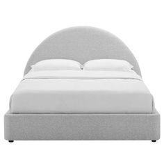 an upholstered bed with white sheets and pillows