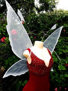 a dress made out of plastic with wings on the front and back, sitting next to flowers