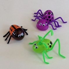 three plastic bugs and one ladybug on a white surface with green, purple, and orange decorations