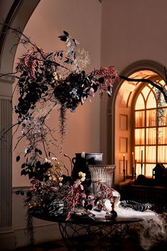 a table with flowers and candles on it in front of an arched window at night