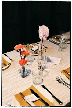 the table is set with place settings and flowers in vases on top of it