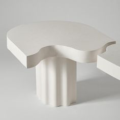 an unusual white table with curved edges sits against a gray background