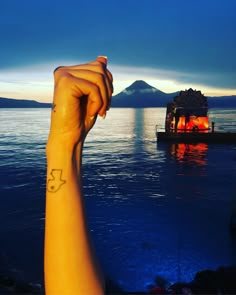 a person's arm with a small tattoo on it and a boat in the background