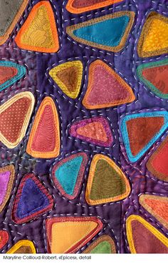 a close up view of a quilt with many different colors and shapes on it,