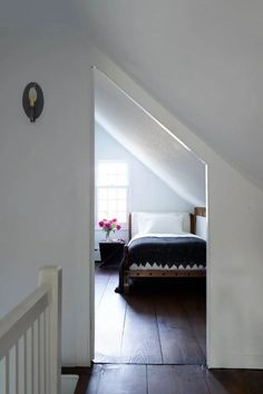 an attic bedroom with white walls and wood floors