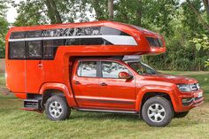 an orange truck with a camper attached to it's bed in the grass