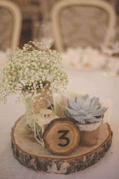 there is a small vase with flowers on top of a tree slice that has the number three in it