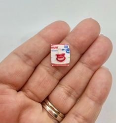 a person holding a tiny ring with the letter c on it's side in their hand