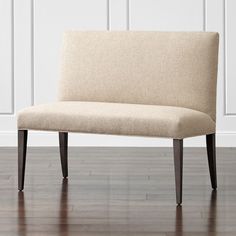 a beige bench sitting on top of a hard wood floor next to a white wall