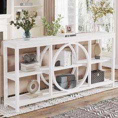 a white console table with books and vases on it in front of a window