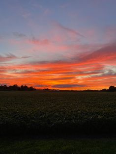 the sun is setting over an open field