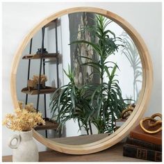 a round mirror sitting on top of a wooden table next to a potted plant