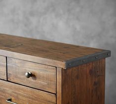 an old wooden dresser with metal handles and knobs on it's sides, against a gray background