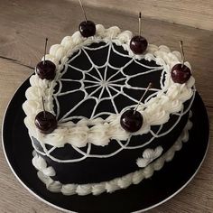 a black cake with white icing and cherries sitting on top of a plate