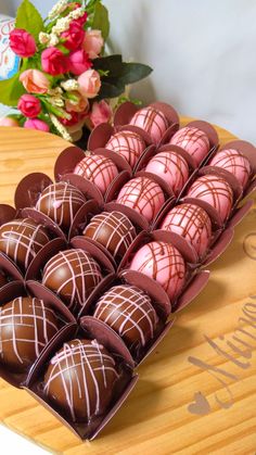 there are many chocolates in the box on the table next to some pink flowers