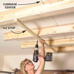 a woman is working on the ceiling in her garage with two drillers attached to it