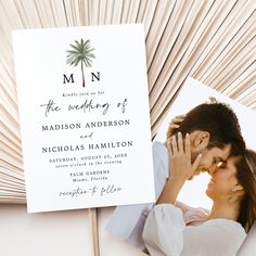 a couple kissing under a palm tree in front of a wedding program card and fan