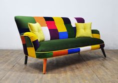 a multicolored couch sitting on top of a hard wood floor next to a white wall