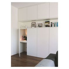 a living room with white furniture and bookshelves on the wall, along with a couch