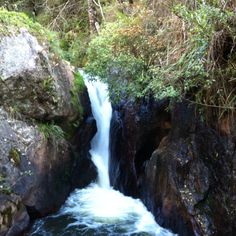 there is a small waterfall in the middle of rocks and water flowing down it's sides