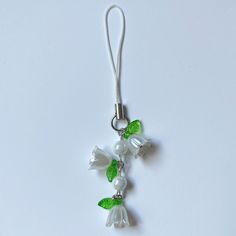 a white flower with green leaves is attached to a lanyard or keychain