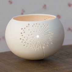 a white vase sitting on top of a wooden table