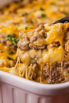 a casserole dish with cheese and ground beef being lifted from the casserole